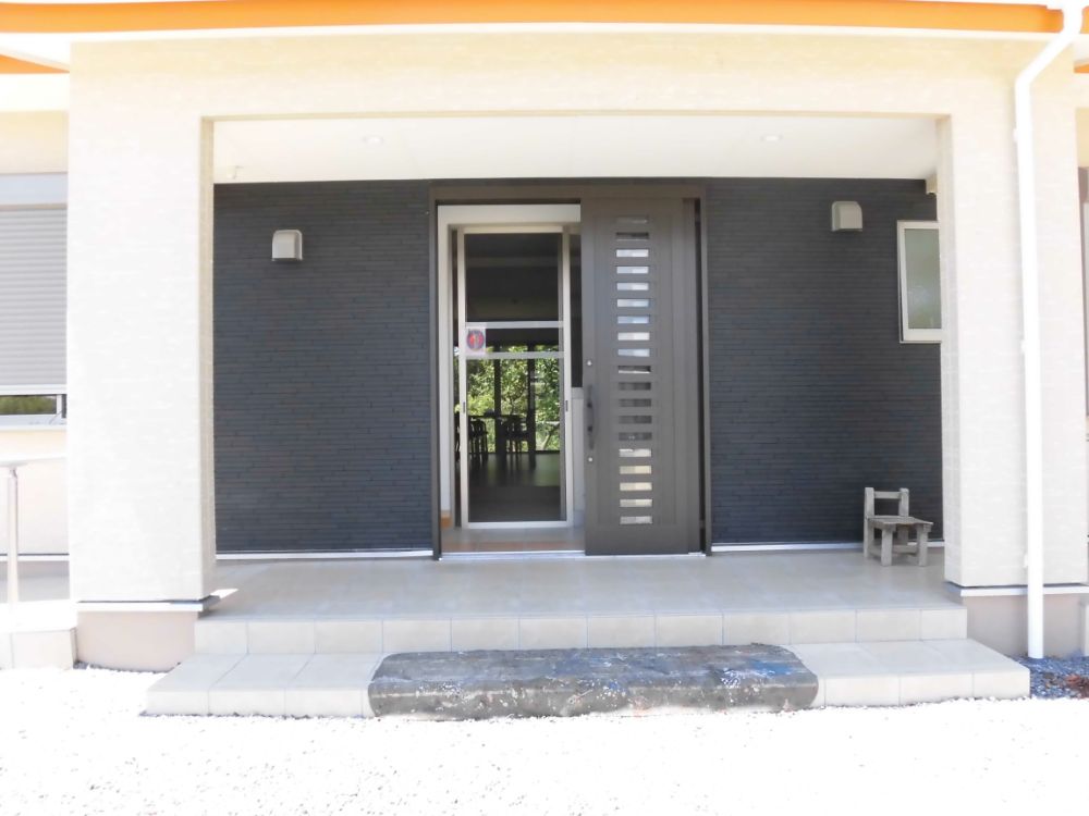 玄関を正面から見た写真。がっちりした印象の黒い引き戸があり、その奥にもう一つ網戸のような引き戸が見える