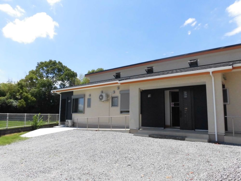 玄関の左側を撮った写真。窓が2つ見える。玄関の左側にもスロープが延びている